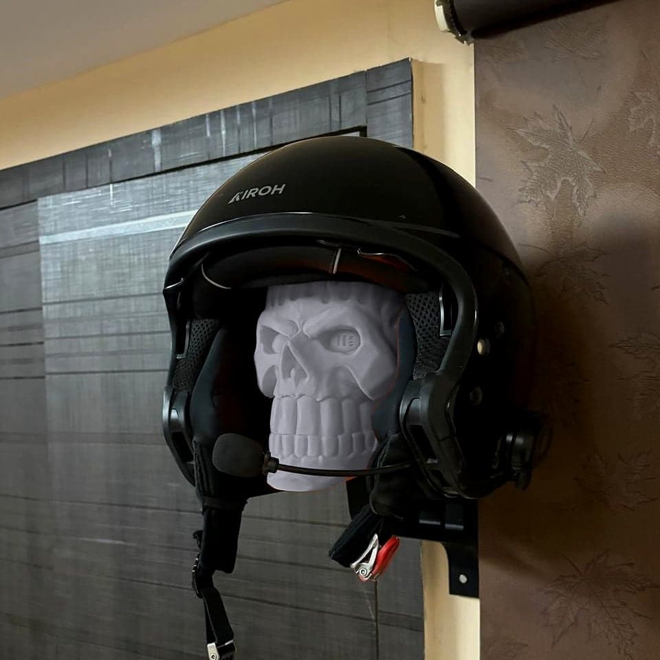 A helmet on the mount against a dark door, the Ghost Grey skull filling the visor